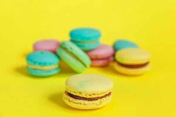 French sweet cookie. Minimal food bakery concept. Pink blue yellow green macaron on yellow background