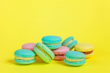 Fransız tatlı kurabiye. Çok az yiyecek ekmek kavramı. Pembe mavi sarı yeşil macaron Sarı zemin üzerine