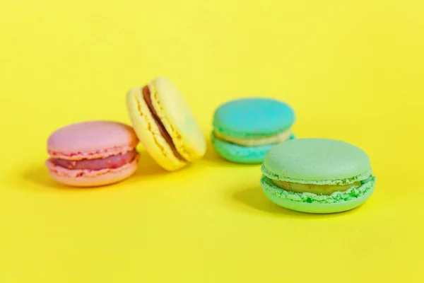 Biscoito doce francês. Conceito mínimo de padaria de alimentos. Rosa azul amarelo verde macaron no fundo amarelo — Fotografia de Stock