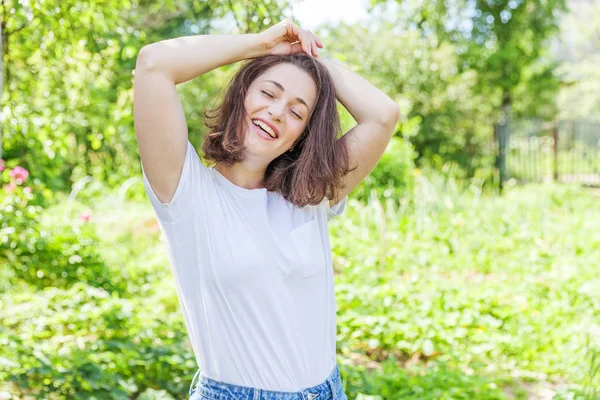 Šťastná dívka se usmívá. Krása portrét mladá šťastná, smějící se brunetka v parku nebo v zahradě — Stock fotografie