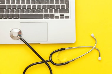 Stetoskop klavye dizüstü bilgisayar sarı arka plan üzerinde izole. Modern tıbbi Bilgi teknolojisi ve sofware gelişmeler kavramı. Bilgisayar ve gadget tanılama ve onarım