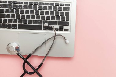 Pembe arka plan üzerinde izole Stetoskop klavye dizüstü bilgisayar. Modern tıbbi Bilgi teknolojisi ve sofware gelişmeler kavramı. Bilgisayar ve gadget tanılama ve onarım