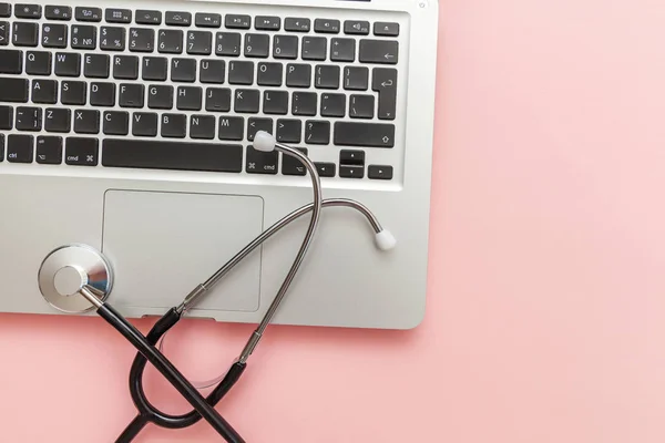 Stethoscope keyboard laptop computer isolated on pink background. Modern medical Information technology and sofware advances concept. Computer and gadget diagnostics and repair