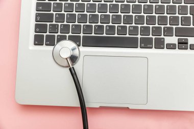 Pembe arka plan üzerinde izole Stetoskop klavye dizüstü bilgisayar. Modern tıbbi Bilgi teknolojisi ve sofware gelişmeler kavramı. Bilgisayar ve gadget tanılama ve onarım