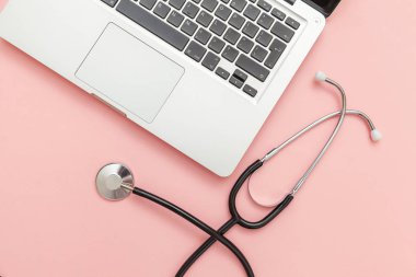 Pembe arka plan üzerinde izole Stetoskop klavye dizüstü bilgisayar. Modern tıbbi Bilgi teknolojisi ve sofware gelişmeler kavramı. Bilgisayar ve gadget tanılama ve onarım