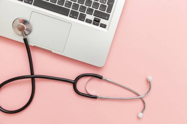 Pembe arka plan üzerinde izole Stetoskop klavye dizüstü bilgisayar. Modern tıbbi Bilgi teknolojisi ve sofware gelişmeler kavramı. Bilgisayar ve gadget tanılama ve onarım