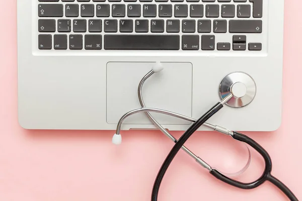 Stethoscope keyboard laptop computer isolated on pink background. Modern medical Information technology and sofware advances concept. Computer and gadget diagnostics and repair