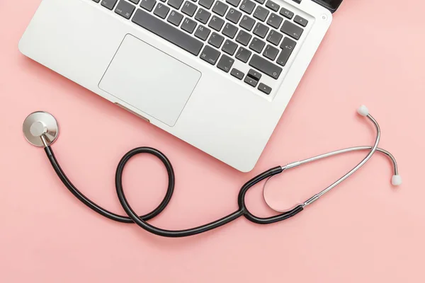 Stethoscope keyboard laptop computer isolated on pink background. Modern medical Information technology and sofware advances concept. Computer and gadget diagnostics and repair