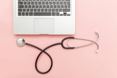 Pembe arka plan üzerinde izole Stetoskop klavye dizüstü bilgisayar. Modern tıbbi Bilgi teknolojisi ve sofware gelişmeler kavramı. Bilgisayar ve gadget tanılama ve onarım
