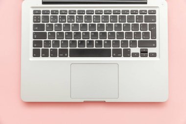 Pembe pastel masa arka planda izole klavye dizüstü bilgisayar. Modern bilgi teknolojisi ve yazılım gelişmeleri