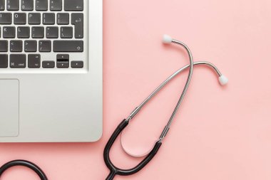Pembe arka plan üzerinde izole Stetoskop klavye dizüstü bilgisayar. Modern tıbbi Bilgi teknolojisi ve sofware gelişmeler kavramı. Bilgisayar ve gadget tanılama ve onarım
