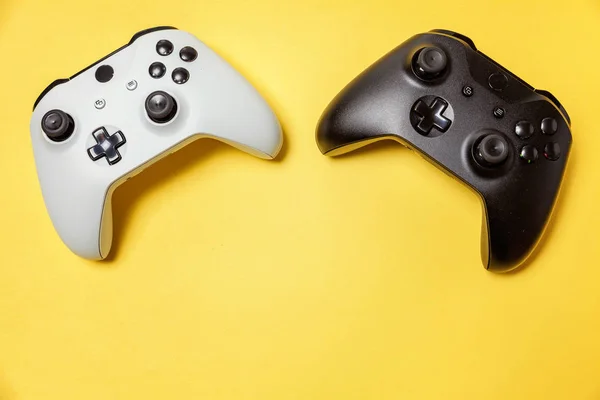 Putih dan hitam dua joystick pada latar belakang kuning. Konsep konfrontasi konfrontasi permainan video kompetisi permainan komputer — Stok Foto