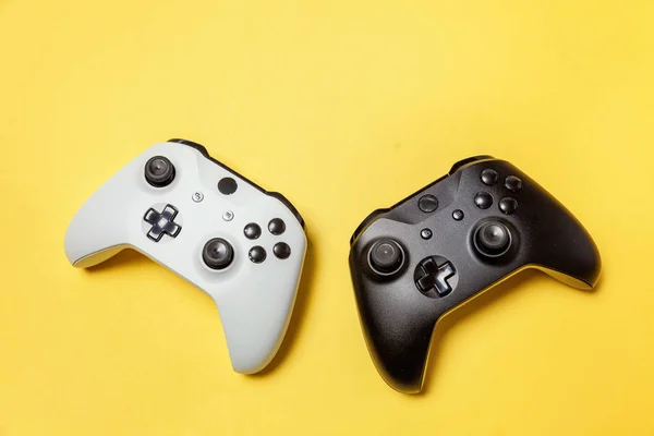 Alb și negru două joystick pe fundal galben. Competiție de jocuri pe calculator Conceptul de confruntare cu controlul jocurilor video — Fotografie, imagine de stoc