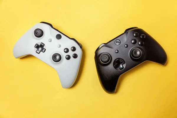 Fehér és fekete két joystick sárga háttéren. Számítógépes játék verseny videogame kontroll konfrontáció koncepció — Stock Fotó