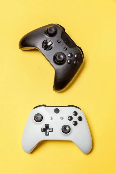 Branco e preto dois joystick no fundo amarelo. Concorrência de jogos de computador conceito de confronto de controle de videogame — Fotografia de Stock