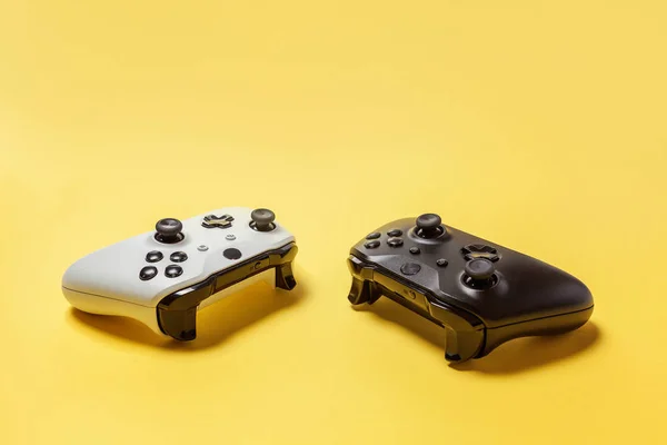黄色の背景に白と黒の2つのジョイスティック。コンピュータゲーム競技大会ビデオゲーム制御対決コンセプト — ストック写真