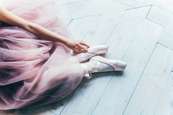 Ballerina hands puts pointe shoes on leg in dance class — Stock Photo, Image