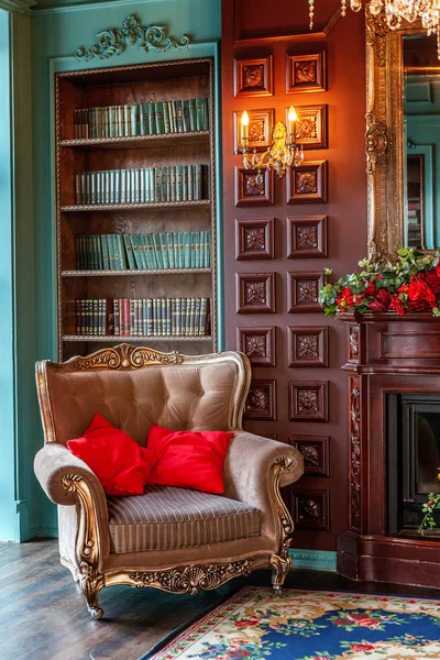 Ev kütüphanesinin lüks klasik iç. Kitaplık, kitap, kol koltuğu, kanepe ve şömineile oturma odası — Stok fotoğraf
