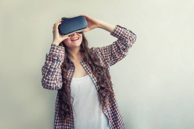 Beyaz arka planda sanal gerçeklik Vr gözlük kask kulaklık kullanarak giyen smile genç kadın. Sanal gerçeklik gözlüğü ile akıllı telefon kullanımı