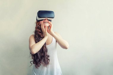 Beyaz arka planda sanal gerçeklik Vr gözlük kask kulaklık kullanarak giyen smile genç kadın. Sanal gerçeklik gözlüğü ile akıllı telefon kullanımı