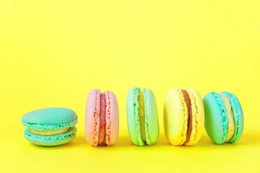 Fransız tatlı kurabiye. Çok az yiyecek ekmek kavramı. Pembe mavi sarı yeşil macaron Sarı zemin üzerine