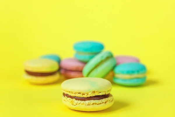 French sweet cookie. Minimal food bakery concept. Pink blue yellow green macaron on yellow background