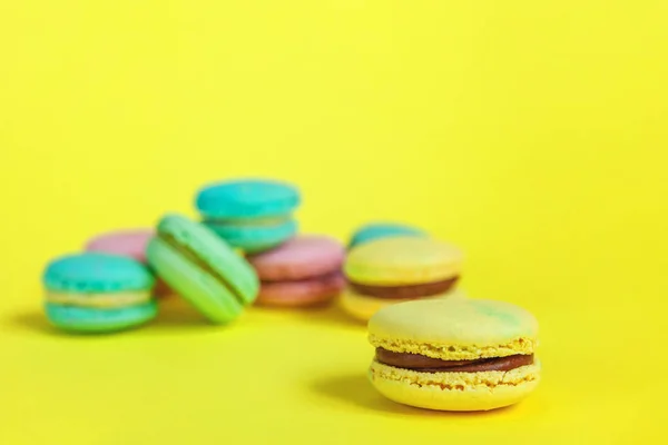 French sweet cookie. Minimal food bakery concept. Pink blue yellow green macaron on yellow background