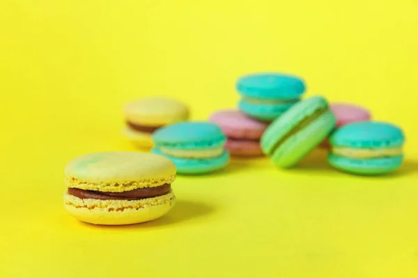 French sweet cookie. Minimal food bakery concept. Pink blue yellow green macaron on yellow background