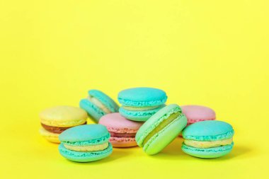 Fransız tatlı kurabiye. Çok az yiyecek ekmek kavramı. Pembe mavi sarı yeşil macaron Sarı zemin üzerine