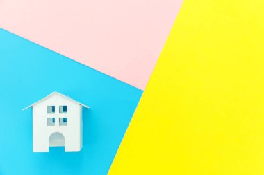 Mavi sarı pembe pastel renkli trendy geometrik arka planda izole minyatür beyaz oyuncak ev