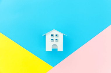 Mavi sarı pembe pastel renkli trendy geometrik arka planda izole minyatür beyaz oyuncak ev