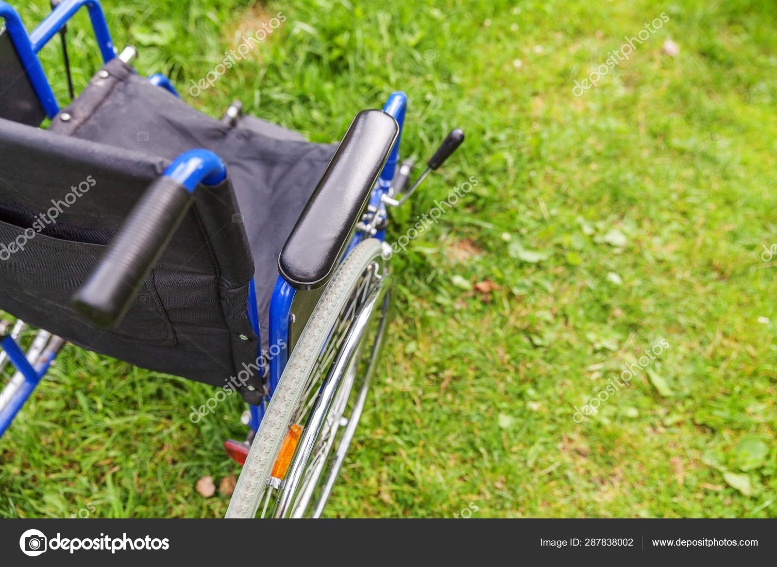 Empty wheelchair standing on grass in hospital park waiting for patient