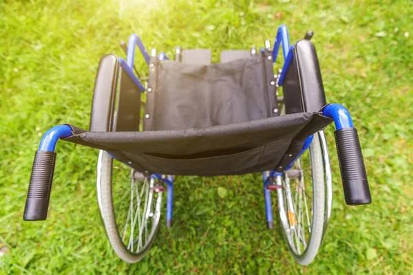 Empty wheelchair standing on grass in hospital park waiting for patient services