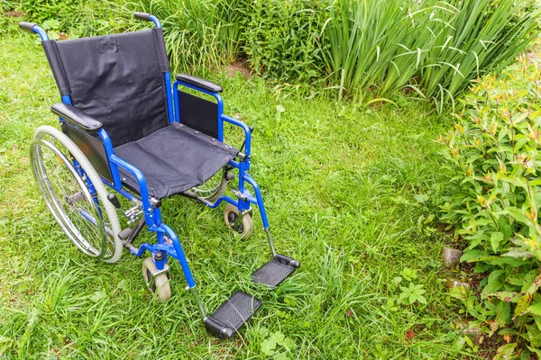 Empty wheelchair standing on grass in hospital park waiting for patient services