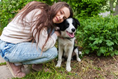 Gülümseyen genç çekici kadın yaz şehir parkı açık arka planda sevimli köpek yavrusu sınır collie sarılma kucaklayan
