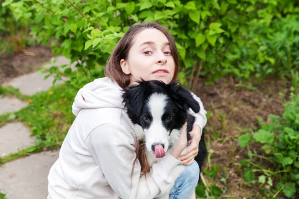 Sonriendo joven atractiva mujer abrazando abrazo lindo cachorro perro frontera collie en verano ciudad parque al aire libre fondo — Foto de Stock