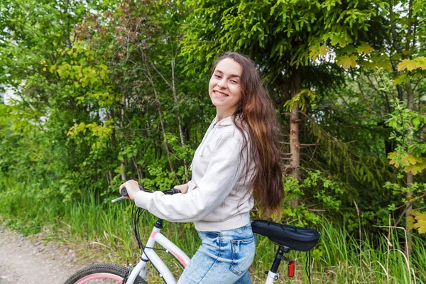 Young woman riding bicycle in summer city park outdoors. Active people. Hipster girl relax and rider bike