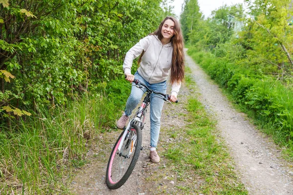 Young woman riding bicycle in summer city park outdoors. Active people. Hipster girl relax and rider bike