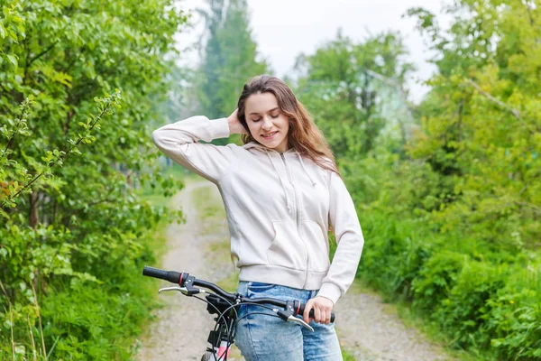 Young woman riding bicycle in summer city park outdoors. Active people. Hipster girl relax and rider bike