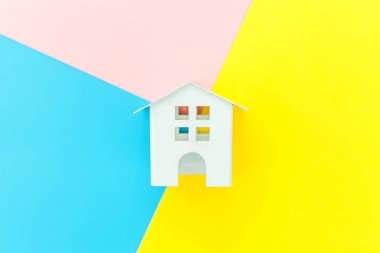 Mavi sarı pembe pastel renkli trendy geometrik arka planda izole minyatür beyaz oyuncak ev
