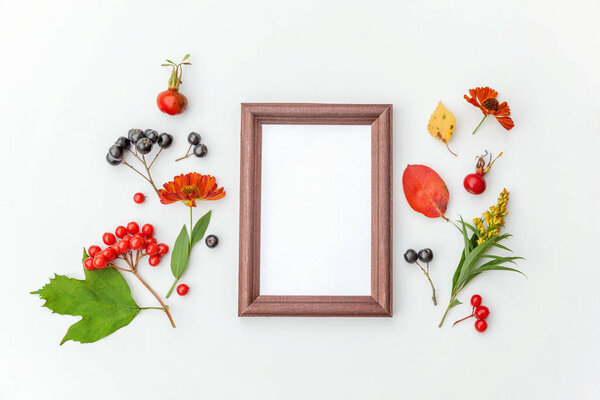 Autumn floral composition. Vertical frame mockup chokeberry rowan berries colorful leaves dogrose flowers on white background