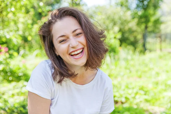 Menina feliz sorrindo. Retrato de beleza jovem feliz positivo rindo morena mulher no parque ou jardim fundo — Fotografia de Stock