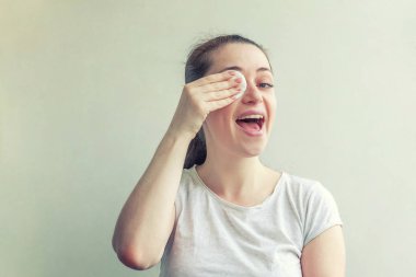 Yumuşak sağlıklı cilt kaldırarak gülümseyen kadın beyaz arka plan üzerinde izole pamuk ped ile makyaj