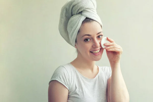 Χαμογελαστή γυναίκα με πετσέτα στο κεφάλι με απαλό υγιές δέρμα αφαίρεση κάνει με βαμβακερό pad απομονωθεί σε λευκό φόντο — Φωτογραφία Αρχείου