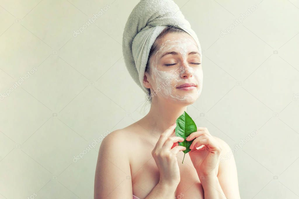 Woman face with green leaf and cream or nourishing mask