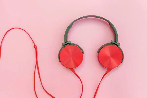 Red headphones with cable isolated on pink pastel colorful background