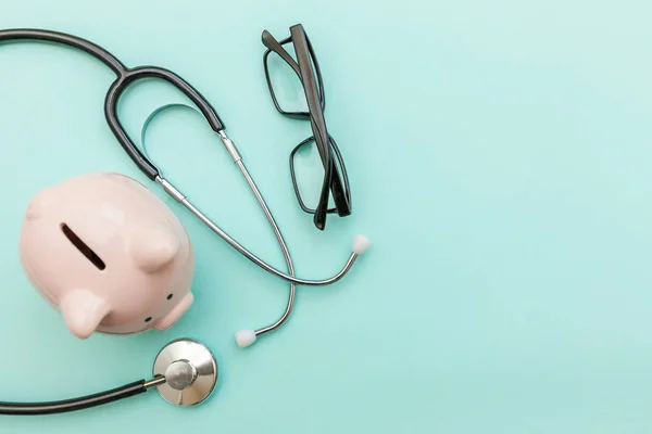 Medicine doctor equipment stethoscope or phonendoscope piggy bank glasses isolated on trendy pastel blue background