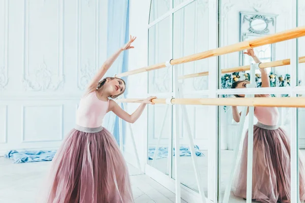 Dans sınıfında pembe tutu etek güzel zarif balerin uygulama bale pozisyonları