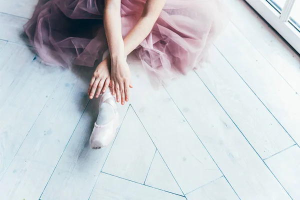 Mãos bailarina coloca sapatos pontiagudos na perna na aula de dança — Fotografia de Stock