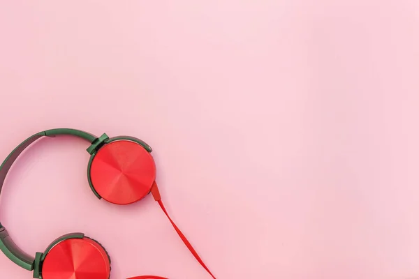 Rode hoofdtelefoon met kabel geïsoleerd op roze pastelkleurige achtergrond — Stockfoto